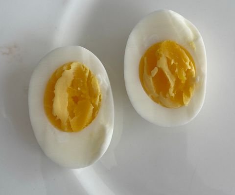 Photo of a large egg boiled 8 minutes, cut lengthwise: white fully set, yolk set at the edge and slightly soft in the centre