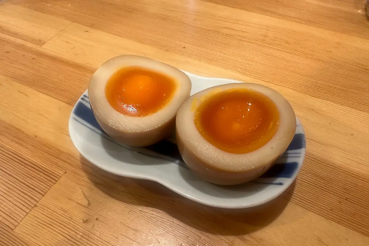 A soy-marinated ramen egg cut in half, showing a jammy orange yolk
